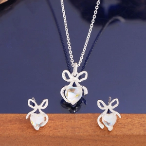 S925 sterling silver bow jewelry set with heart-shaped moonstone on a dark reflective surface