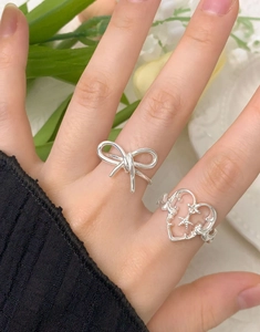 Gros plan de bagues nœud et cœur évidé en argent sterling S925 sur un doigt