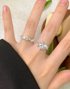 Macro shot of silver bow heart rings and pearl ribbon detail on female hand