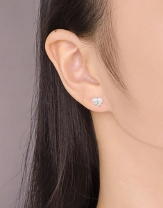 Gros plan de boucles d'oreilles cœur en argent S925 portées avec texture 3D brillante