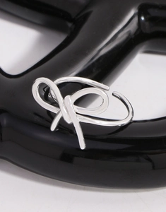 Vue détaillée d'une bague nœud argentée ajourée sur un support chic au fini métallique