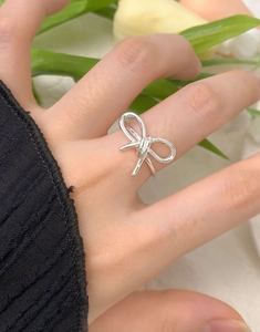 Détail de la bague nœud évidé en argent S925 portée avec fond tulipe élégant