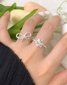 Gros plan de bagues en argent S925 avec nœud minimaliste et motifs floraux texturés