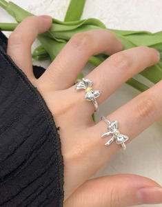 Detail of S925 silver bow rings with yellow zircon on a model hand with tulips
