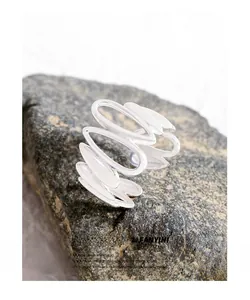 Detailed macro view of S925 sterling silver irregular wave rings on a natural stone base