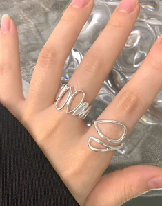 Detail shot of irregular water drop rings in 925 silver on hand with glass background