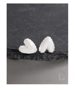 Gros plan de boucles d'oreilles cœur en argent S925 avec finition mate texturée