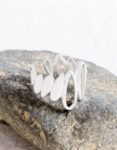 Macro shot of irregular layered water drop silver ring on dark textured stone