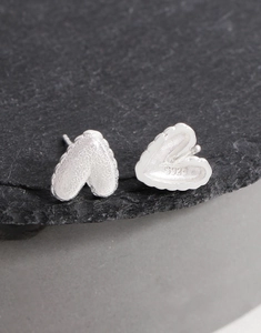 Gros plan de boucles d'oreilles cœur en argent S925 avec fini mat sur pierre sombre