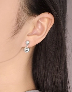 Close-up of irregular liquid metal style silver drop earrings on a model's ear
