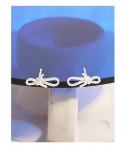 Close-up of S925 sterling silver bow knot stud earrings on white pedestal