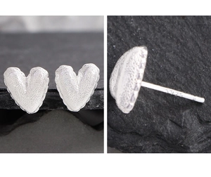 Détail de boucles d'oreilles cœur en argent S925 avec texture métallique martelée unique