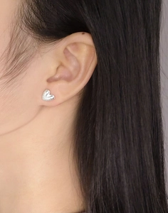 Gros plan de boucles d'oreilles cœur en argent S925 avec texture martelée sur le lobe