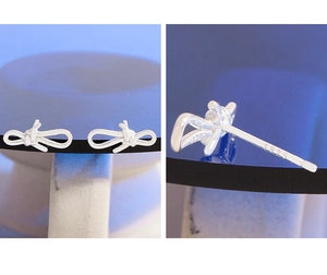 Close-up of asymmetric silver bow earrings with S925 hallmark on the ear needles
