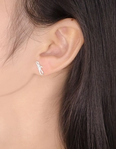 Macro shot of S925 sterling silver bow knot stud earring on a female earlobe