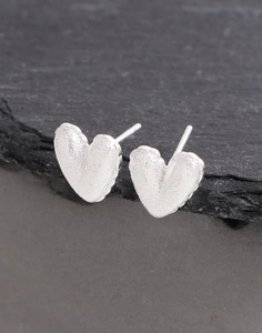 Gros plan sur boucles d'oreilles cœur en argent S925 avec texture martelée sur pierre