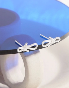 Macro shot of S925 sterling silver bow earrings with smooth polished metallic finish