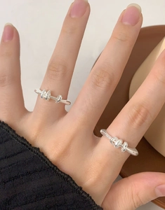 Close-up of S925 sterling silver minimalist knot rings worn on finger for layered styling