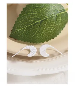 Detail of S925 sterling silver moon earrings with textured radial lines on ceramic plate