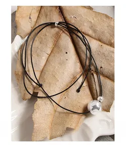 Detail of S925 sterling silver ball pendant necklace with adjustable black cord on tabletop