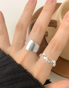 Close-up of irregular silver geometric ring and delicate zircon ring worn on model hand