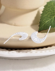 Macro view of S925 sterling silver C-shaped earrings with fine radial carved textures