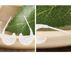 Macro detail of S925 sterling silver crescent earrings with sunburst texture