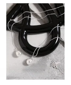 Close-up of minimalist silver water drop pendants with high-polish mirror finish on grey stone