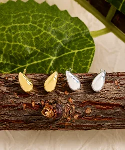 Gros plan de boucles d'oreilles goutte d'eau minimalistes en or et argent sur écorce