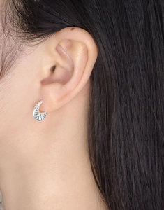 Close-up of S925 silver huggie earrings with sunburst texture worn on the earlobe