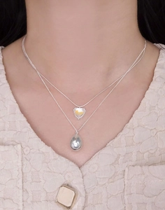Close-up of layered S925 silver necklaces with heart stone and water drop pendants