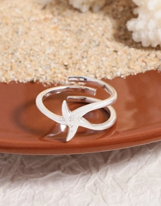Macro shot of S925 sterling silver starfish open ring on sand and coral background