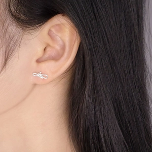 Minimalist S925 sterling silver bow earrings shown on a model with high contrast