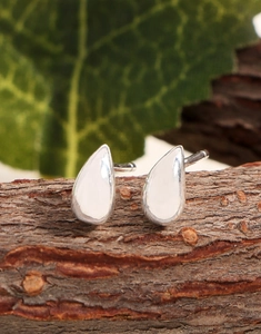 Gros plan sur des boucles d'oreilles goutte en argent sur bois avec une feuille verte