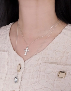 Close-up of a double-layered S925 silver necklace featuring cross and teardrop pendants