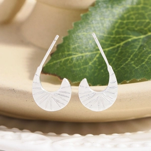 Irregular moon-shaped silver stud earrings with radial texture on ceramic edge