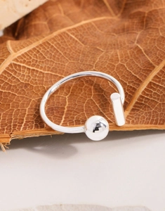 Detail shot of asymmetric S925 sterling silver open ring on textured leaf background