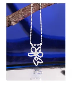 Detail of silver S925 hollow flower pendant necklace displayed on a wooden branch