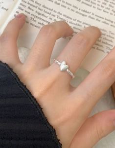 Close-up of S925 sterling silver heart ring with matte texture on an open book