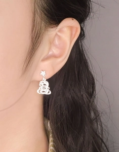 Close-up of S925 silver star and Christmas tree drop earrings worn on a female ear