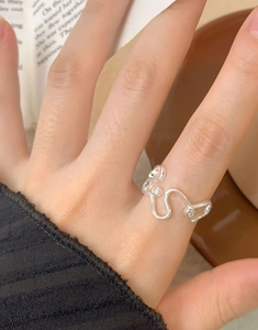 Nahaufnahme eines unregelmäßigen S925 Silberwellenrings mit Zirkonia am Finger