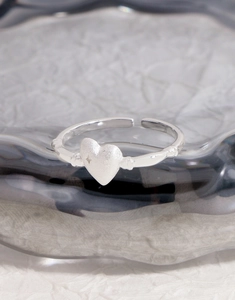 Detail of S925 sterling silver ring featuring a matte heart and star engraving on grey tray
