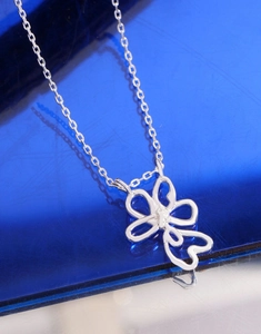 Macro view of S925 silver necklace featuring a hollow flower pendant on a blue surface