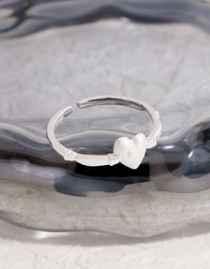 Macro detail of matte heart ring featuring bamboo-style band in silver-tone finish