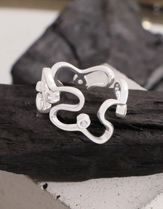 Makrofoto eines S925 Silberrings mit unregelmäßiger Form und Zirkonia auf Kohle