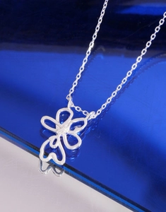 Macro shot of silver floral hollow pendant with sleek chain on reflective surface