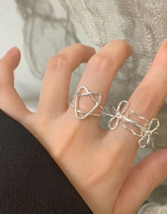 Detailaufnahme von zwei S925 Silberringen mit Herz- und Schleifendesign an einer Hand