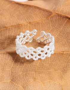 Macro detail of S925 sterling silver twisted woven ring on a rustic natural leaf background