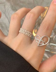 Detail of S925 silver irregular heart ring and woven band on finger for elegant styling
