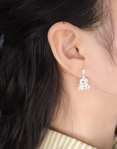 Detail of silver S925 Christmas tree earring with zircon star worn on woman ear